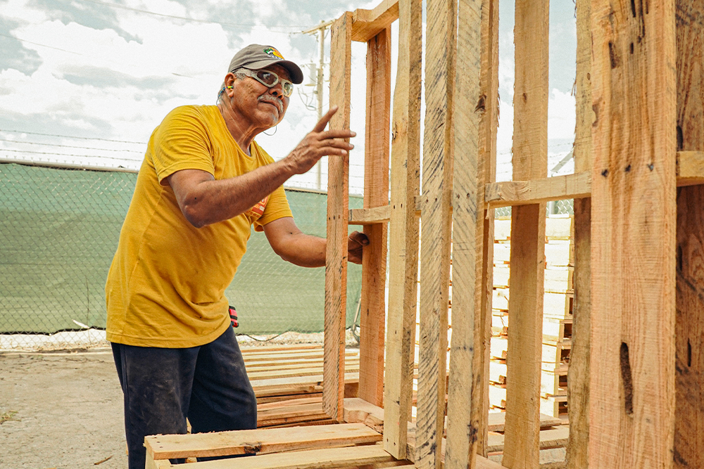 stack of wooden pallets on a loading dock with a worker adjusting them